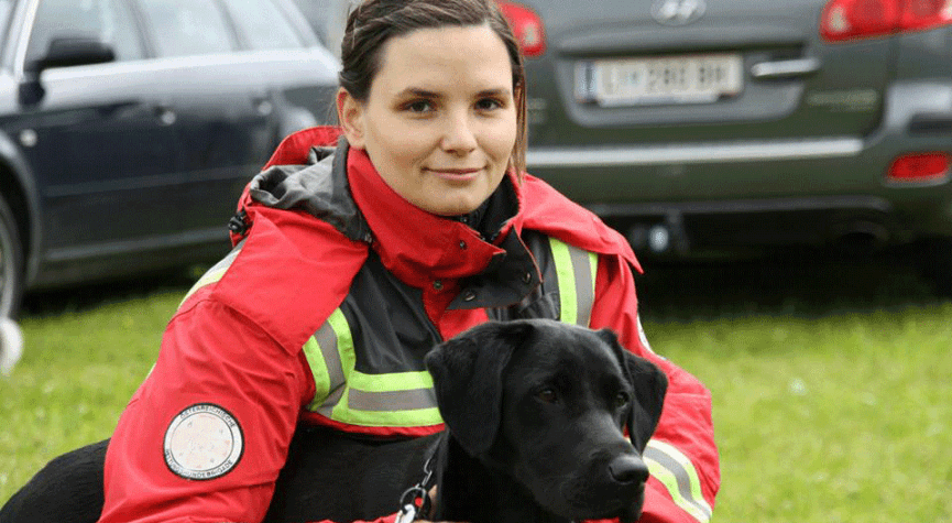 Babsi sitzt bei Kiwi im Gras und die beiden warten auf ihren Einsatz bei der Rettungshundestaffel